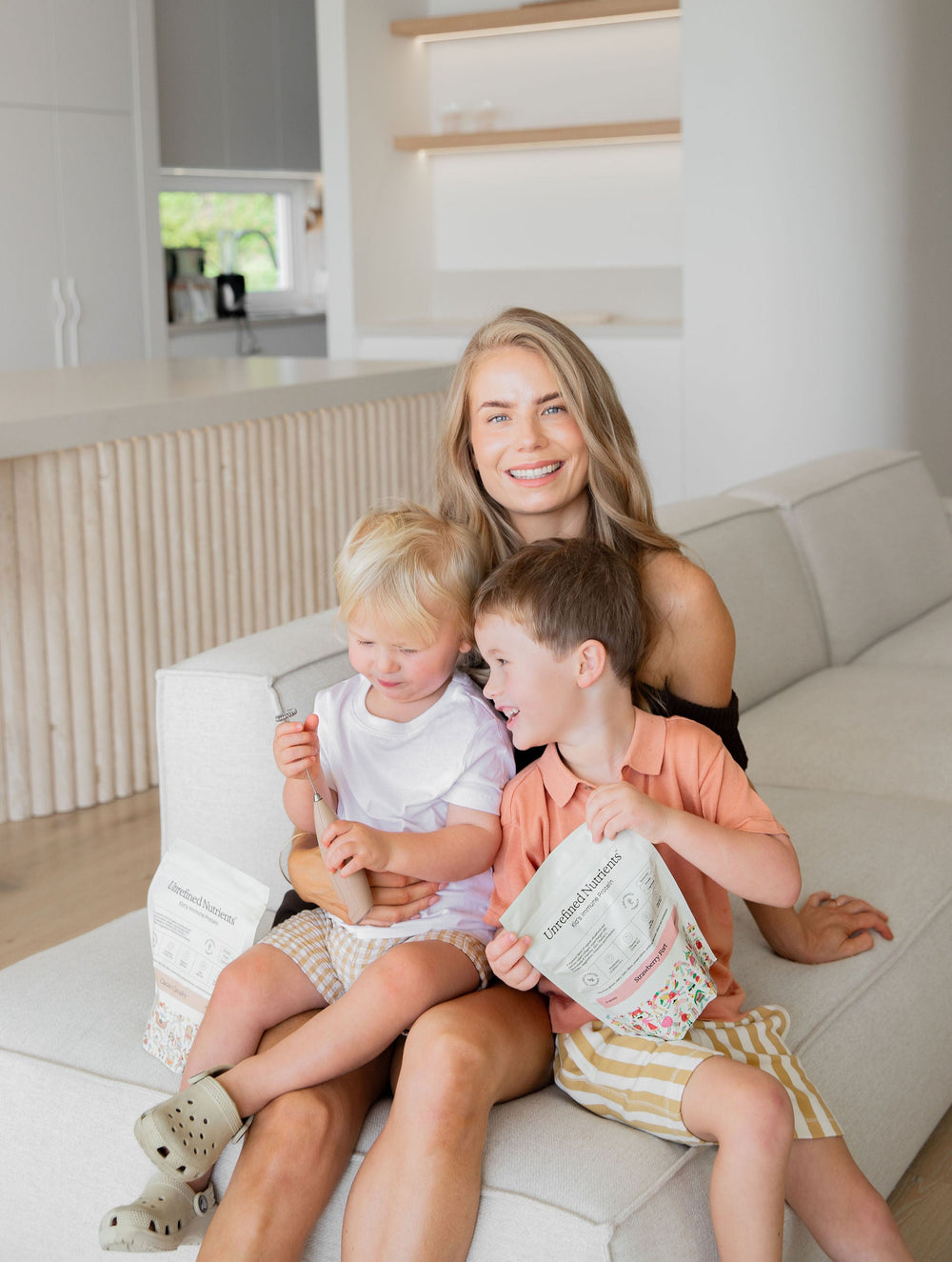 Nicola on the couch with two of her boys and a pouch of Kids Immune Protein