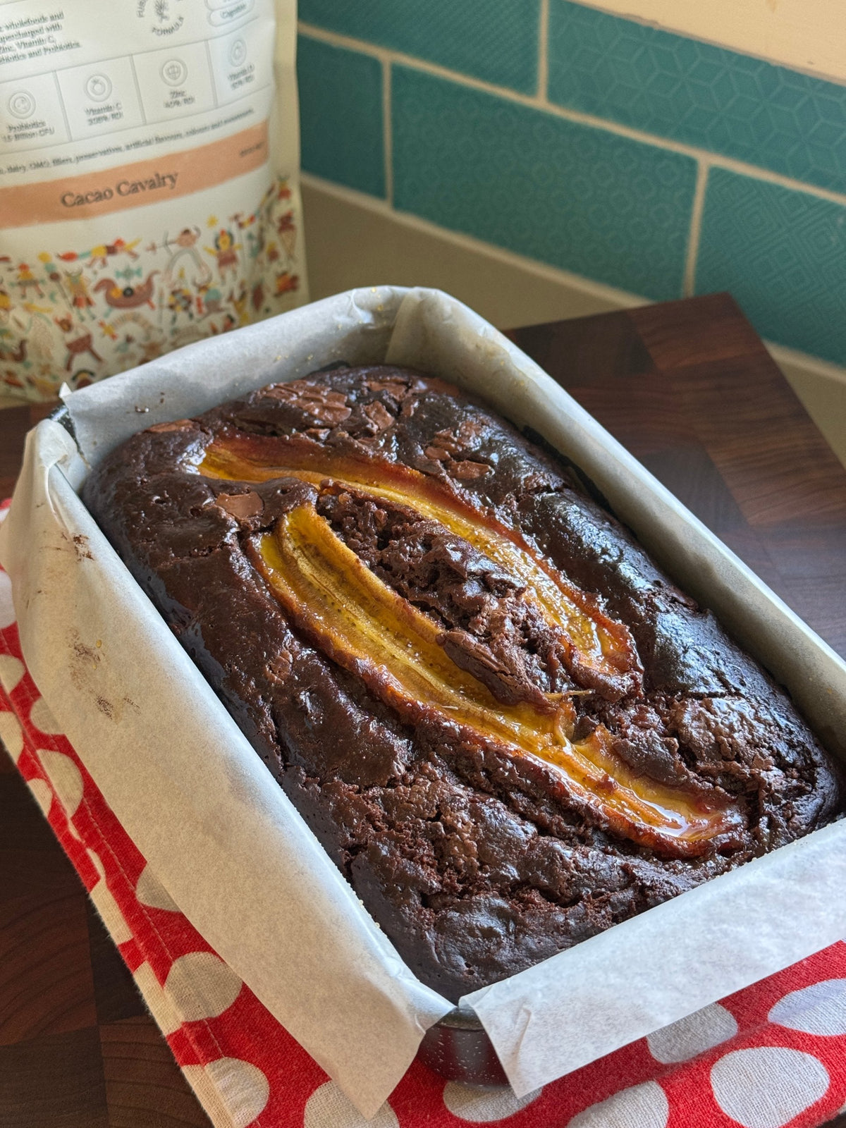 Chocolate banana protein bread in a lined loaf tin with Kids Immune Protein Cacao Cavalry behind