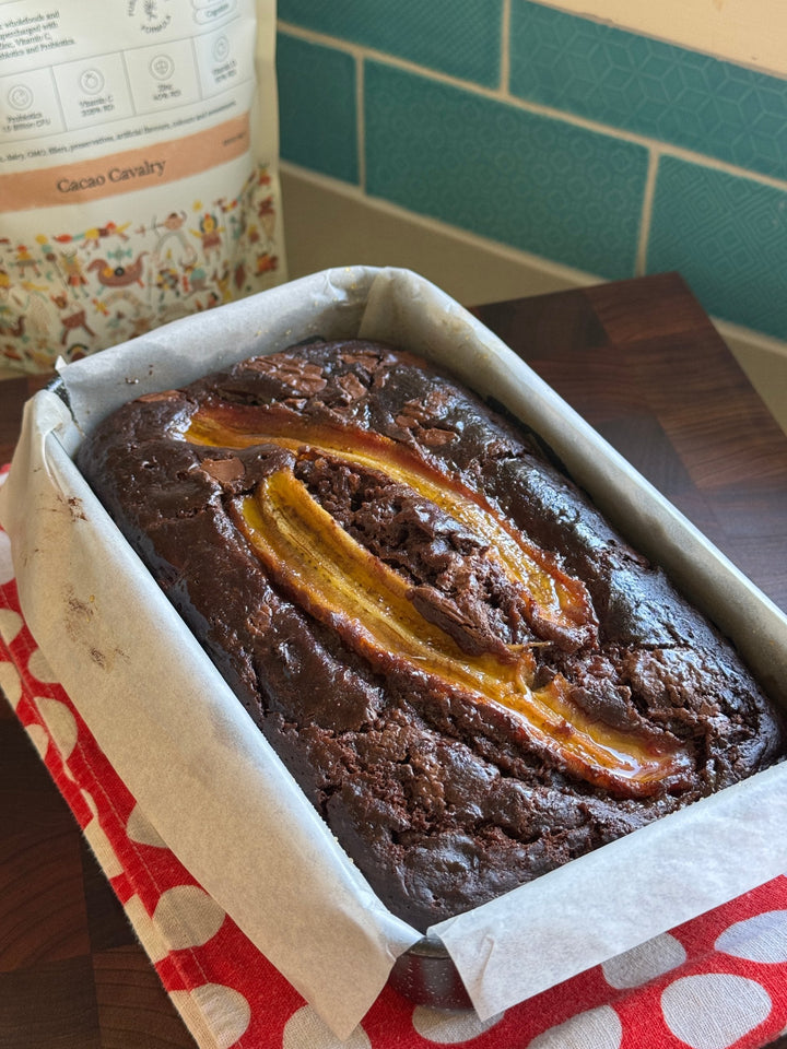 Chocolate banana protein bread in a lined loaf tin with Kids Immune Protein Cacao Cavalry behind